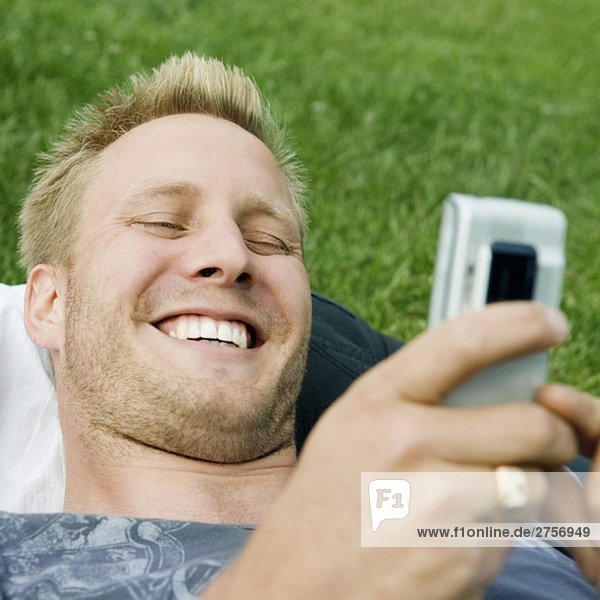 Man with phone lying on lawn