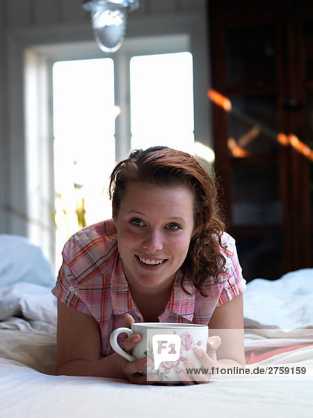 A young Scandinavian woman drinking tea in the bed Sweden.