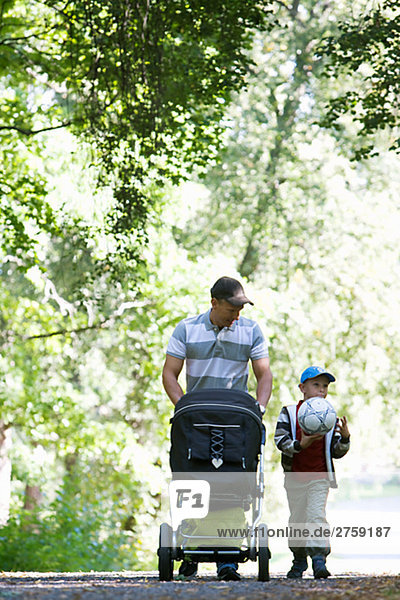 Vater und Sohn zu Fuß in einem Park am sonnigen Tag Schweden.