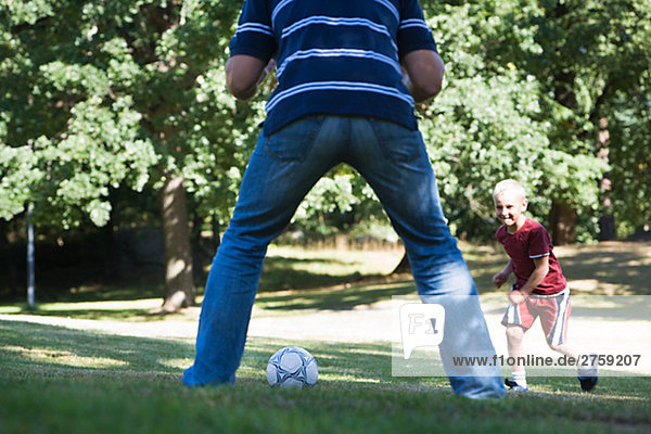 Vater und Sohn spielen Fußball in einem Park am sonnigen Tag Schweden.
