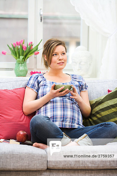 A pregnant woman sitting in a couch Sweden.