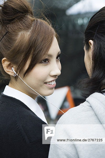 Young female listening to earphones  smiling at boyfriend  cropped view
