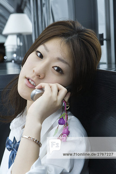 Young female using cell phone  looking at camera