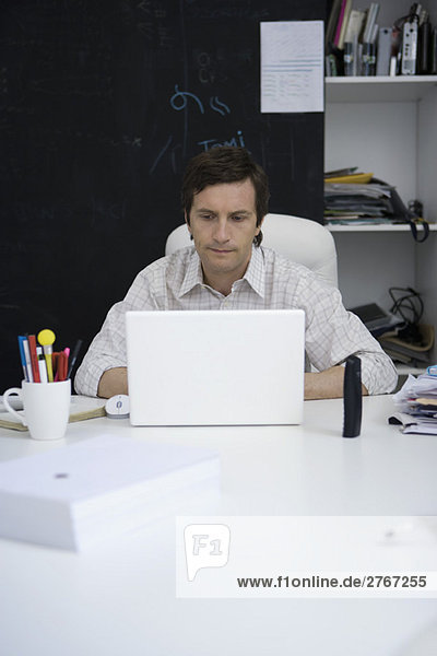Mann arbeitet am Laptop am Schreibtisch
