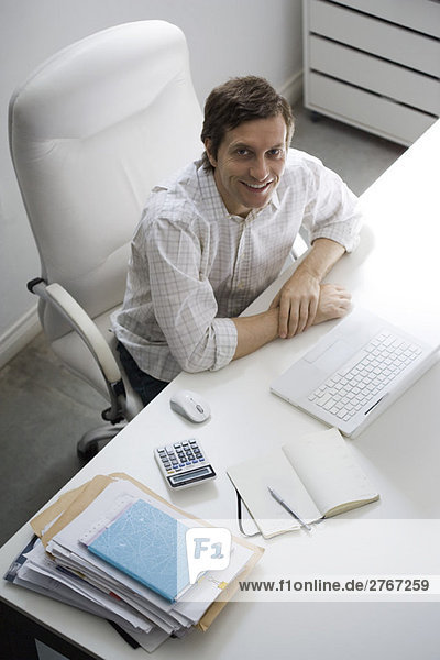 Man sitting at desk  smiling up at camera