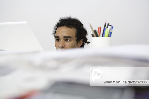 Man working at desk  obscured behind pile of documents