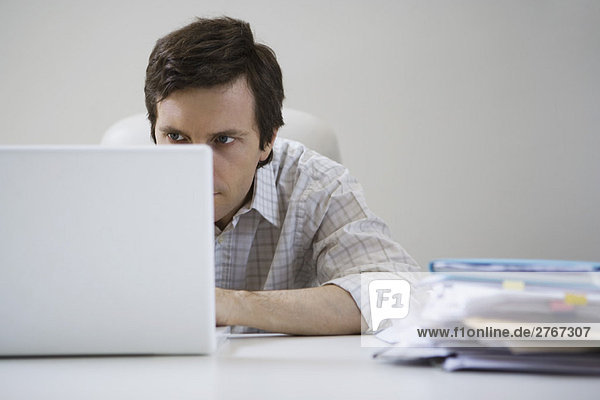 Man hunched over  working on laptop