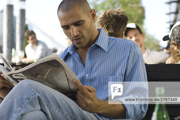 Man reading newspaper outdoors