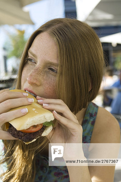 Young woman biting into hamburger