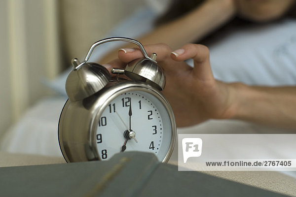 Woman's hand silencing alarm clock