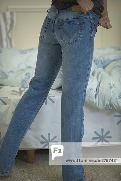Frau zieht sich eng anliegende Jeans an  Schnittansicht