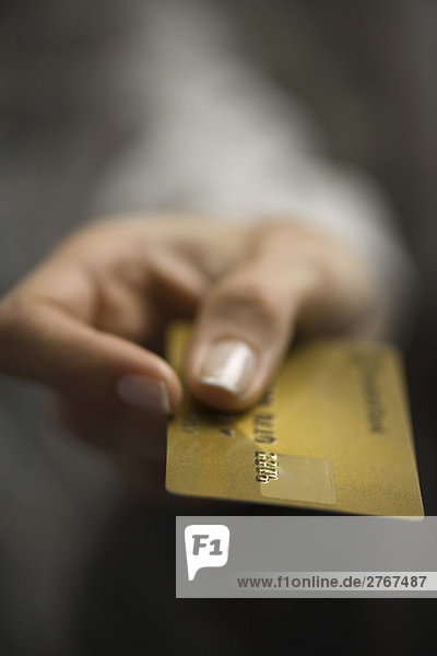 Woman's hand holding out credit card  extreme close-up