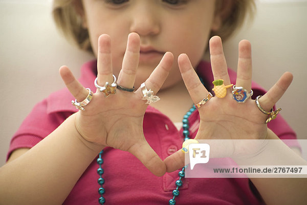 Kleines Mädchen mit mehreren Plastikringen an den Fingern  Nahaufnahme