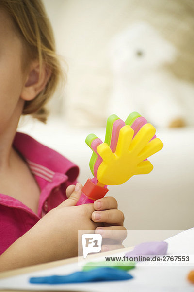 Kleines Mädchen hält Plastik-Klatschspielzeug  Ausschnittansicht