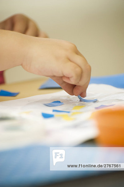 Kindercollage mit Kleber und Papier  zugeschnittene Ansicht der Hände