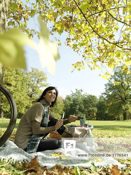 Seitenansicht reife Frau hält Scheibe Brot und lächelnd in Park