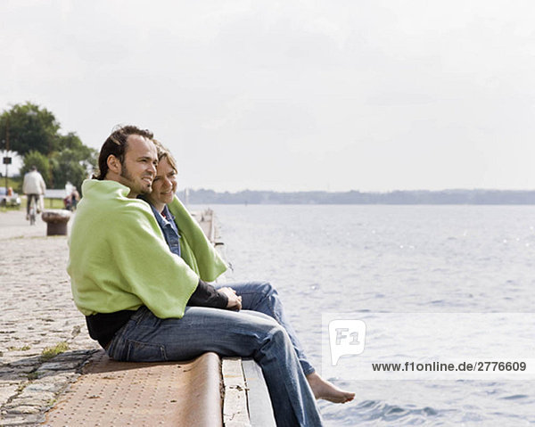Mann und Frau starren auf einen See.