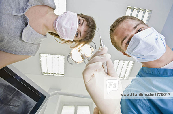 Zahnarzt mit zahnärztlichem Werkzeug und Assistentin