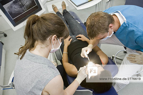 Zahnarzt mit Patient und Assistentin