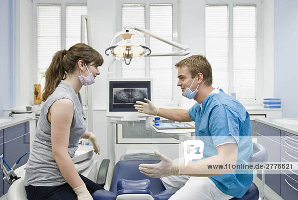 Zahnarzt im Gespräch mit der Assistentin