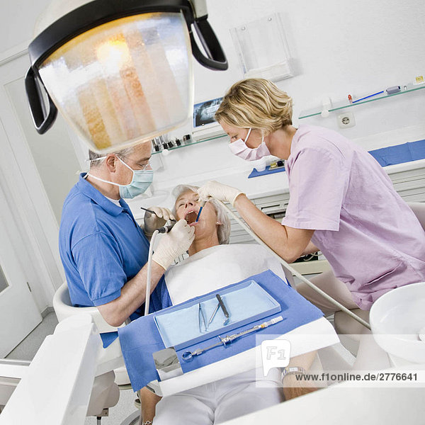 Zahnarzt und Assistentin bei der Arbeit am Patienten
