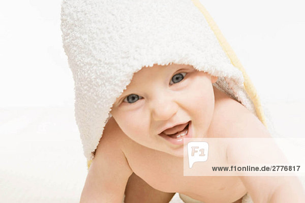 Ein lächelndes Baby mit einem Handtuch.