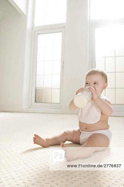 Ein Baby  das aus einer Milchflasche trinkt.