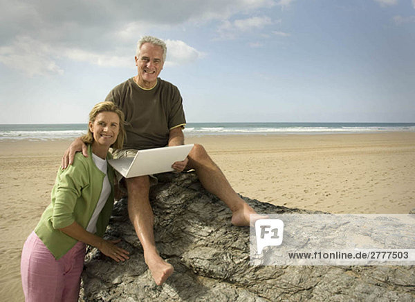 Paar am Strand mit Laptop-Computer
