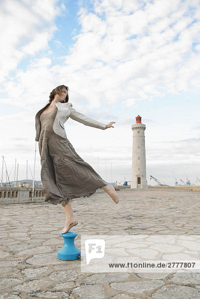 Frau beim Springen vor dem Leuchtturm