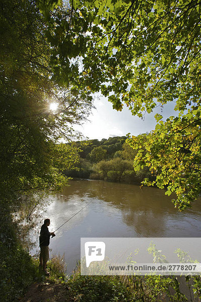 Fisherman standing on a river bank.