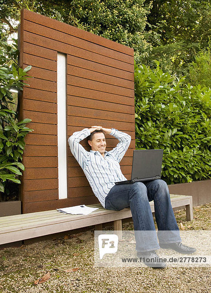 Geschäftsmann entspannt mit Laptop im Freien