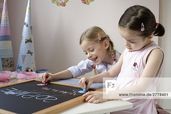 Zwei Mädchen auf Tafel schreiben