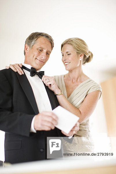 Paar in Abendgarderobe hält Hochzeitseinladung