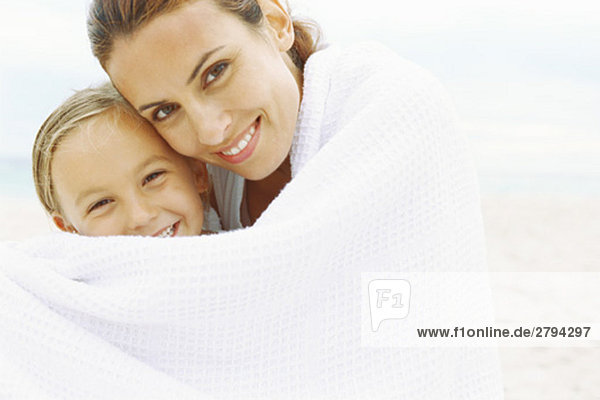 Mutter und Tochter in Handtuch gewickelt am Strand  Portrait