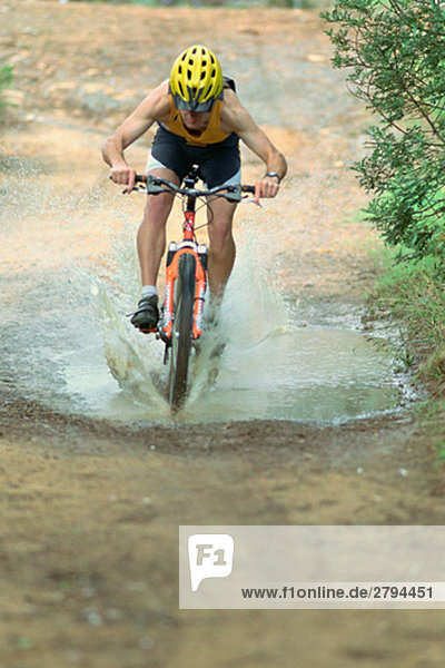 Cyclist riding through puddle on mountain bike