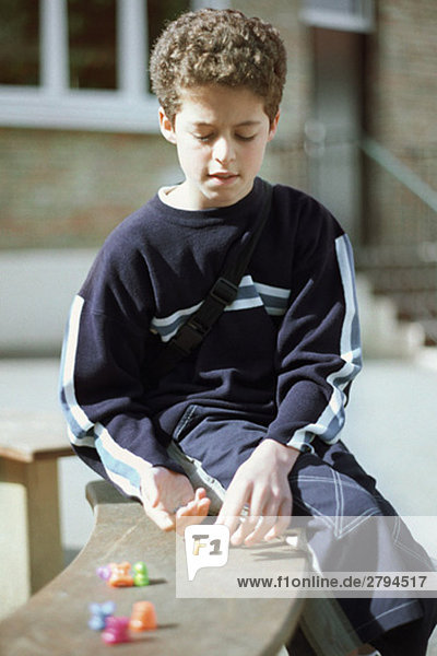 Junge auf Bank sitzend  spielend