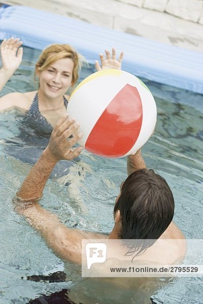 Frau und Mann spielen mit einem Wasserball im Schwimmbecken