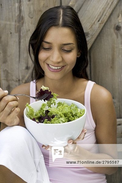 Junge Frau isst grünen Salat