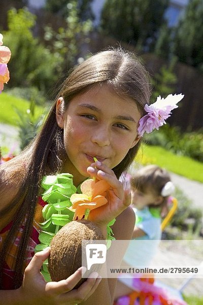 Girl drinking coconut milk out of coconut at children's party