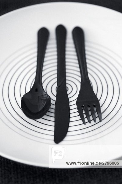 Schwarzes Plastikbesteck auf einem Teller