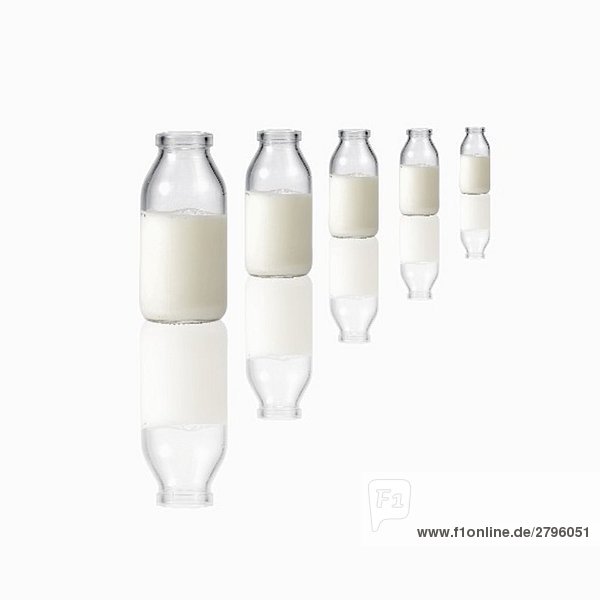 Fünf Milchflaschen auf spiegelnder Fläche