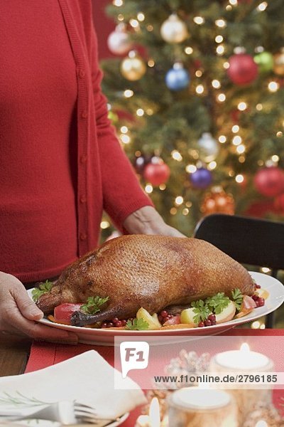 Frau serviert gebratene Ente zu Weihnachten