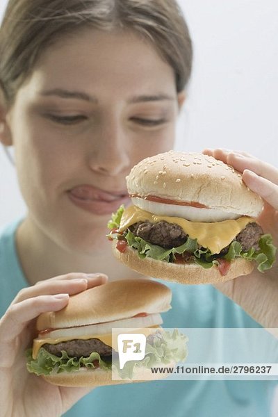 Junge Frau hält zwei saftige Cheeseburger