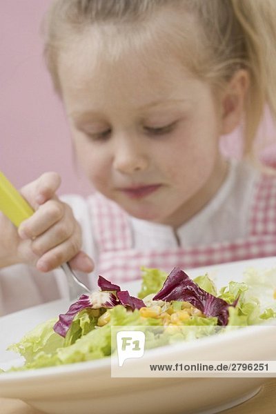 Kleines Mädchen isst Blattsalat mit Mais