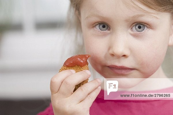 Kleines Mädchen hält Chicken Nugget mit Ketchup