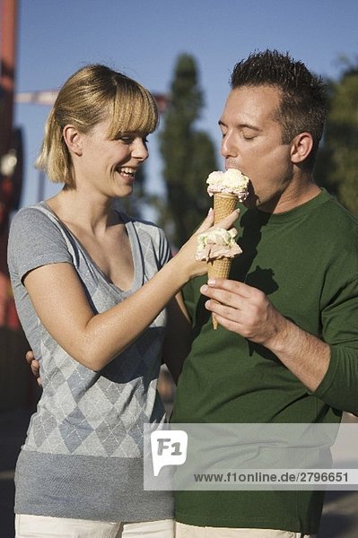 Cheerful couple with ice cream cones out of doors