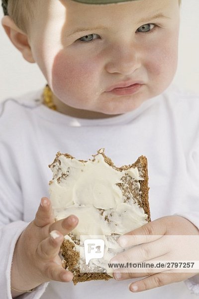 Kleinkind hält angebissenes Butterbrot