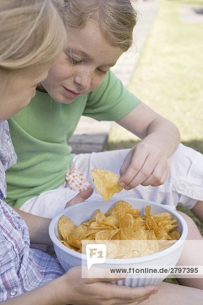Zwei Mädchen essen Chips im Freien