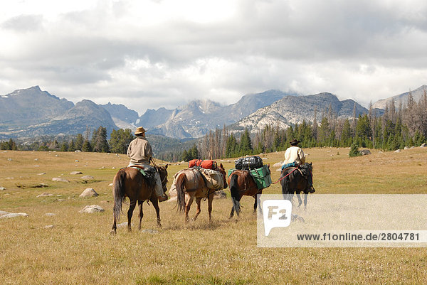 People riding horses with mountain range in background  Wind River Range  Fish Creek Park  Wyoming  USA
