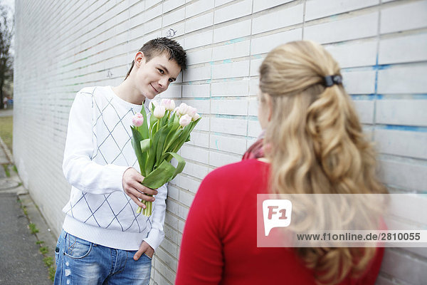 Teenager Blumen zu seine Freundinnen geben